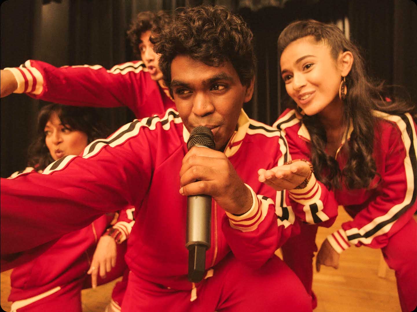 Young people in matching red tracksuits take the microphone to rap