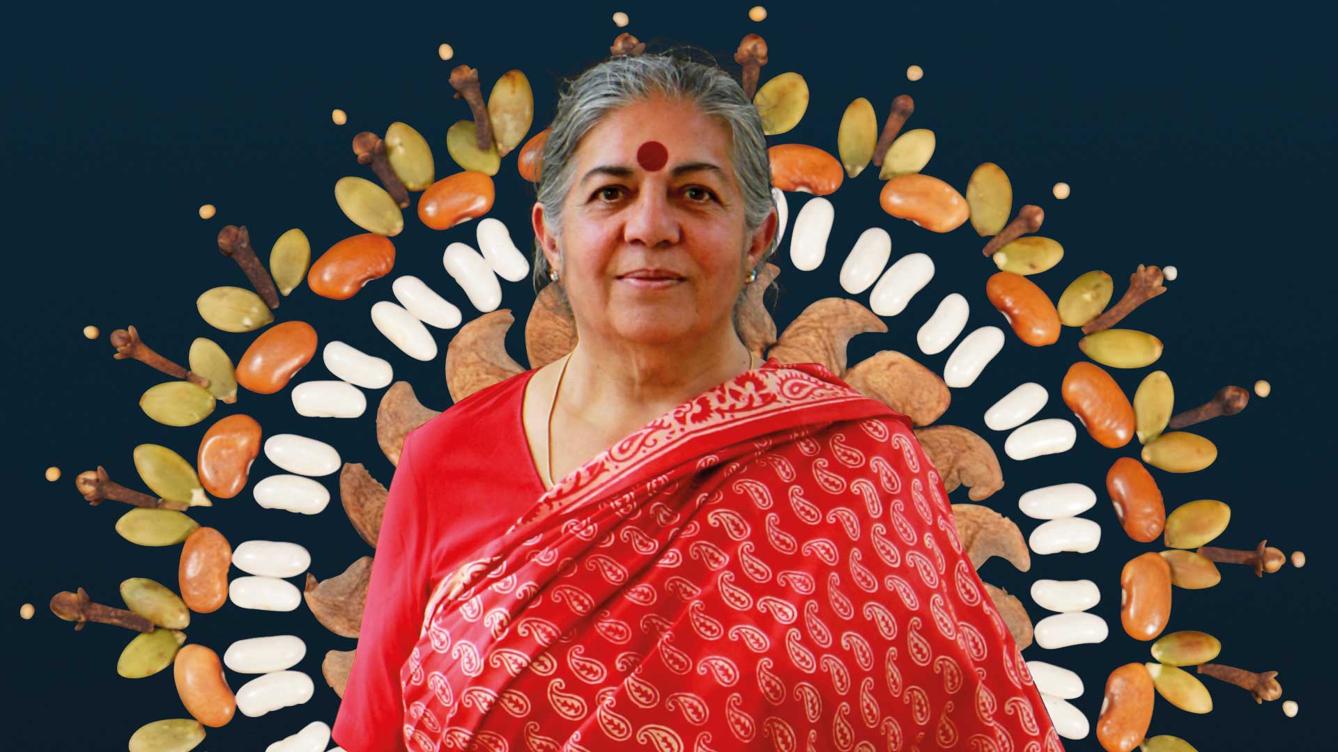 A photo of an older Indian woman in a bright red sari has been superimposed over an arrangement of differently shaped and colored seeds, giving the effect of a statue of a deity surrounded by a ring of fire