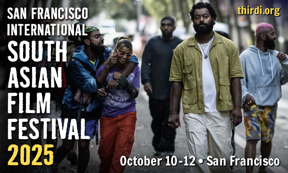 A group of young hip South Asian teams walk laughing in a group, toward the camera, in an urban street in France. But the central young man looks at the camera in a brooding manner that might foretell a problem coming.